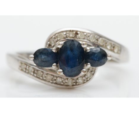 A 9ct white gold three stone sapphire ring, diamond set shoulders, K, 2.3gm 