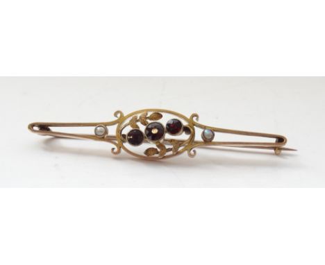 EDWARDIAN GARNET AND SEED PEARL BAR BROOCHin nine carat gold, the central three garnets in leaf decorated pierced setting, 5.