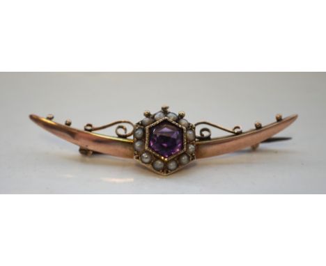 EDWARDIAN AMETHYST AND SEED PEARL SET BAR BROOCHin nine carat gold, the crescent bar with central amethyst and seed pearl clu