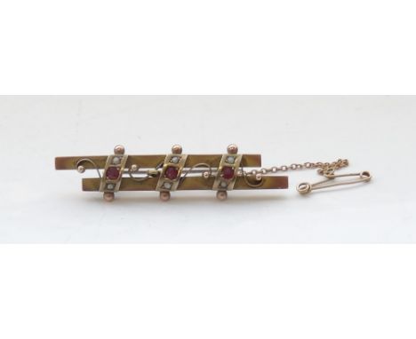 EDWARDIAN RUBY AND SEED PEARL BROOCHeach of the three rubies with a seed pearl above and below, on nine carat gold double bar