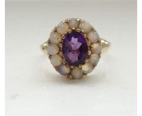 AMETHYST AND OPAL CLUSTER DRESS RINGthe central oval cut amethyst in twelve round cabochon opal surround, on nine carat gold 