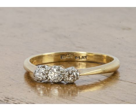 An 18ct gold and platinum three stone diamond ring, the old cuts in platinum claw settings on a fine gold shank, ring size L,