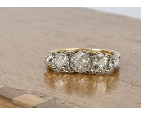 An Edwardian five stone diamond dress ring, the five old cuts in graduated setting interspersed with diamond chips on a scrol