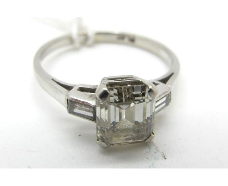 An Emerald Cut Single Stone Diamond Ring, (6.5 x 5.5mm) corner claw set, between baguette cut inset shoulders, stamped "Plat"