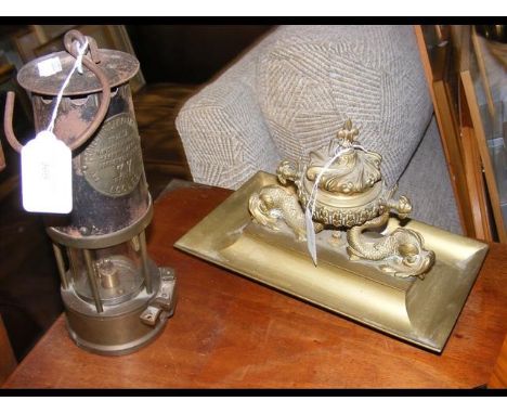 A Victorian brass pen and inkstand with Dolphin mounts, together with an old Miner's lamp 