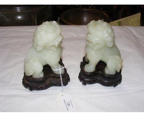 A pair of 11cm high carved jade Dogs of Fo on intricate wooden stands CONDITION REPORTGood condition
