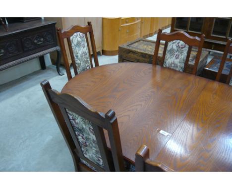 An extending oval topped oak old charm dining table together with six tapestry seat and back upholstered dining chairs