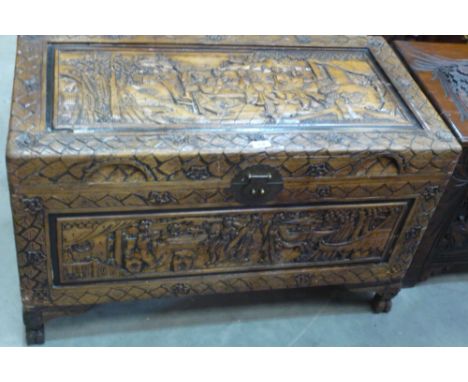 A light comphor wood chest with heavily carved oriental scenes to all panels, 99cm x 52cm x 61cm high