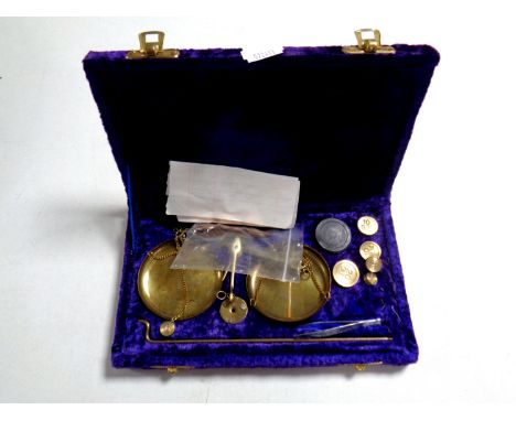 A set of miniature brass balance scales with weights in a fitted purple velvet box  