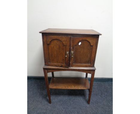 An Edwardian oak double door cabinet on raised legs with under shelf fitted two internal drawers 