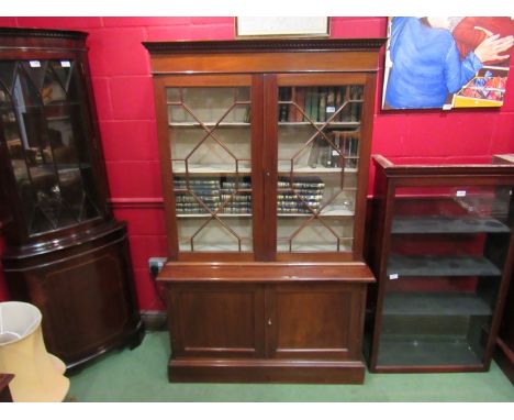 A 1930's Regency style mahogany glazed bookcase, dentil-moulded to over two door cupboard plinth base (doors shrunk) 172cm ta