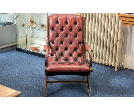 A Leather Chesterfield Armchair in ox blood leather and button back and seat. Raised on four tapered legs with cross stretche