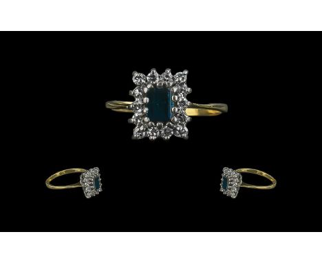 A Central Step Cut Sapphire surrounded by 14 round cut diamonds hallmarked rubbed, tests 18ct. Ring size L.