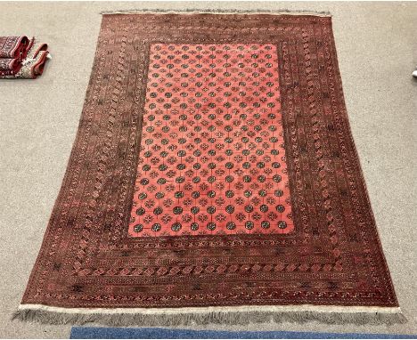 Large red ground Persian Bokhara carpet, the field decorated with traditional repeating Gul motifs, multi-band guarded border