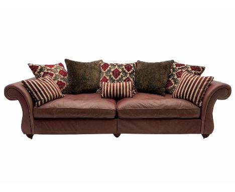 Grande traditional design three seat sofa, upholstered in salmon pink leather with contrasting scatter cushions, brass castor