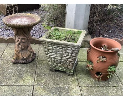 A composite bird bath, in the form of a tree, depicting bearded men faces as the trunk, 53cm tall, together with a terracotta