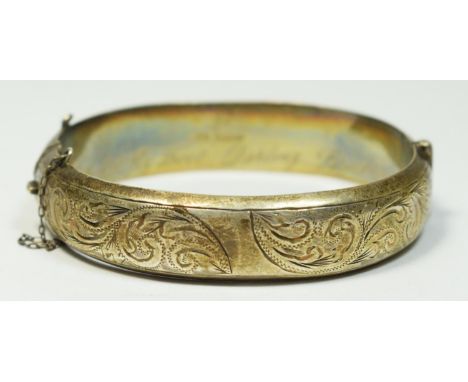 A silver hinged bangle, Birmingham 1962, engraved scroll decoration, presentation inscription, 21gm 