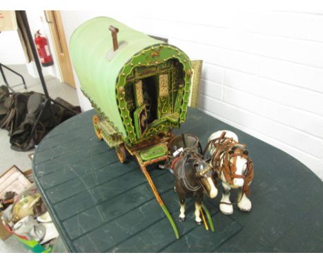 A decorative wooden gypsy caravan with two ceramic horses in harness