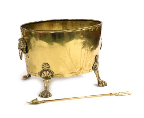 An oval brass planter, with lion's head and ring handles, raised on four paw feet, 46cm wide, together with a brass toasting 