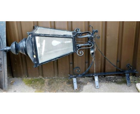 A cast iron garden lantern, with four glazed sides, raised on a scrolling wall bracket, approx 160cm high. 