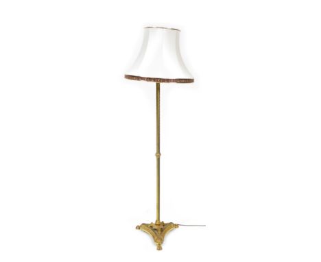 A late Victorian brass standard lamp, converted to electricity, with a fluted and lappet cast column, raised on three claw fe