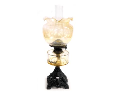 An early 20thC Duplex cast iron and amber glass oil lamp, with glass chimney and amber glass shade, 53cm high. 