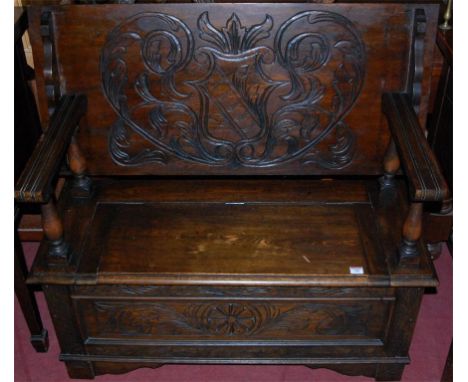 An early 20th century low relief line carved oak fold over monks bench, having typical hinged box seat base