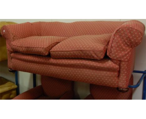 An Edwardian red floral upholstered three piece suite comprising triple sofa and pair of armchairs, each on turned walnut bun