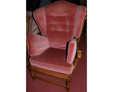 An Ercol mid elm three piece suite comprising twin sofa, two armchairs, and a footstool