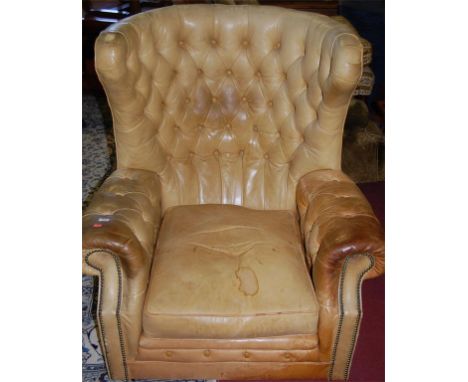 A light tan leather button back and further studded wingback club armchair