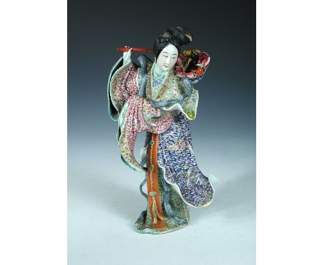 A 20th century figure of a lady, she stands wearing windswept colourful robes with a basket of fruit and flowers suspending f