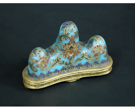 A cloisonne brush rest, four character mark of Qianlong, modelled as three turquoise mountains decorated with scrolling lotus