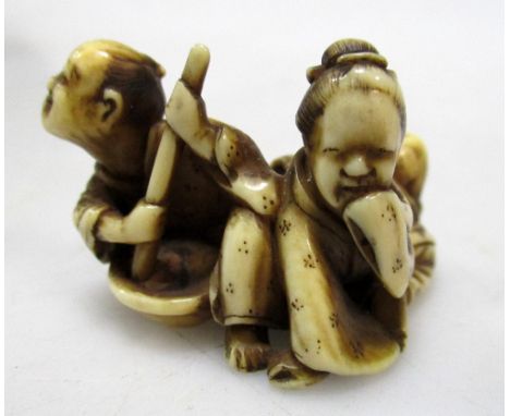 A late 19th/early 20th century ivory netsuke carved as a man stirring a bowl with a a bamboo pole, the noxious smell causing 