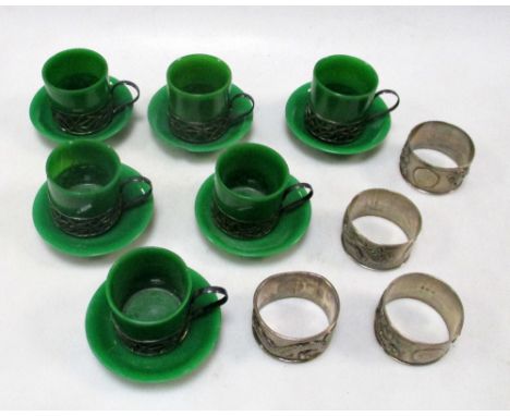 A set of four silver napkin rings together with six silver mounted Pekin green glass demitasse coffee cups and saucers, one o