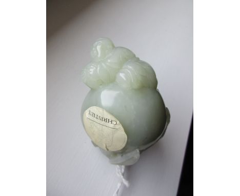 A 19th century nephrite jade boy and peach pendant, the boy reclining on his stomach on top of the giant peach, one foot rest