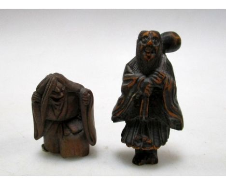 Two 19th century wooden netsuke, one depicting a man standing with a pack on his shoulders, he wears a cloak of leaves, 5.5cm