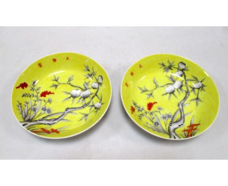 A pair of yellow ground saucers painted in grey with peaches, the heads of the millet and three character inscriptions 'Studi