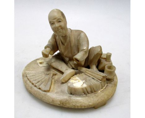 An early 20th century ivory group together with two blue and white porcelain boxes, the first of a man seated making fans, la