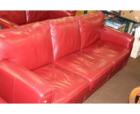 A RED LEATHER THREE PIECE SUITE, CONSISTING OF A THREE SEATER AND TWO SEAT AND A POUFFE  