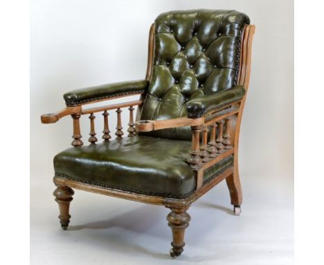 A Victorian oak and green upholstered gentleman's library armchair, with a button back and padded arms, with slide out suppor