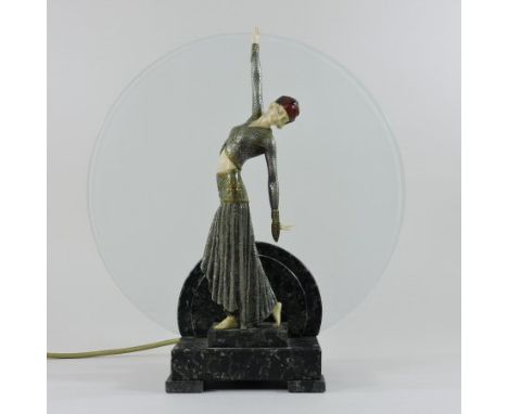 An Art Deco style composition figural table lamp, modelled as a young lady, standing before a circular opaque glass shade, on