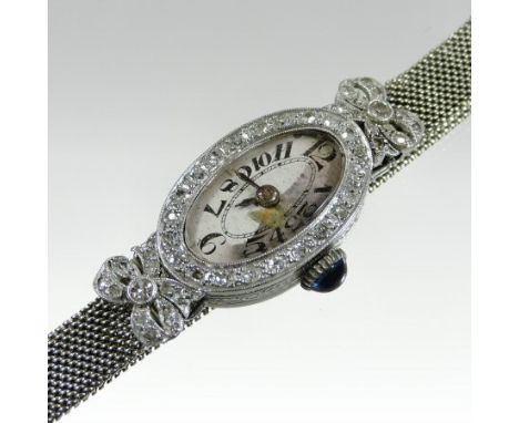 A 1950's platinum and diamond set cocktail watch, the oval dial with a diamond set bezel and cabochon gem set winder, decorat