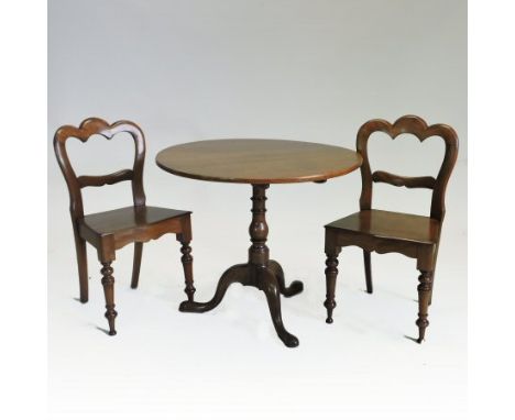 A George III oak and elm circular tilt top occasional table, with a baluster column and tripod base, 84cm diameter, together 