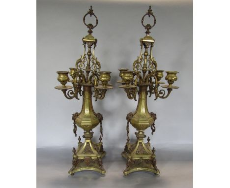A good pair of brass four branch candelabra, with rococo style sconces, upon a faceted baluster column and swept square plate