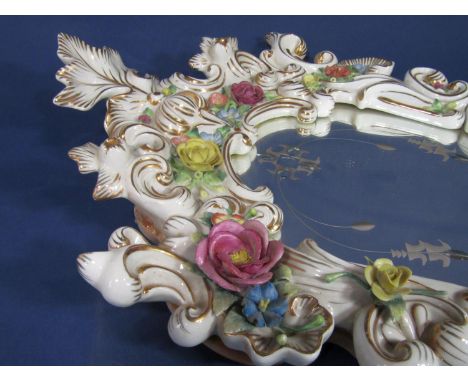 A continental decorative ceramic mirror frame with scrolling detail and applied floral detail, etched shaped glass mirror pla