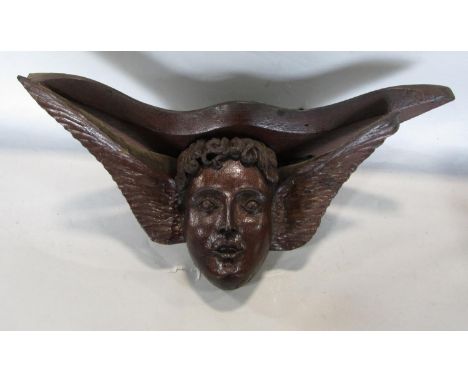 A carved oak wall hanging or bracket in the form of a winged cherubs face, 37cm long 