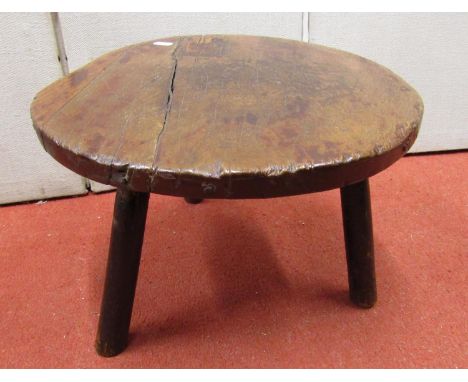 A primitive oak stool, the circular top cut from a simple piece, 39cm diameter, raised on three stick supports in ash wood, 2