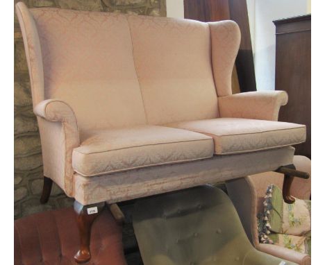 A Parker Knoll two seat sofa in the Queen Anne style with light pink floral patterned upholstered finish and loose seat cushi