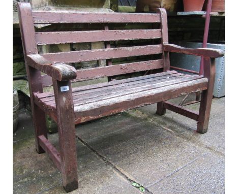 A stained and weathered teakwood two seat garden bench with slatted seat and back, labelled to side rail Wood Fern 120 cm lon