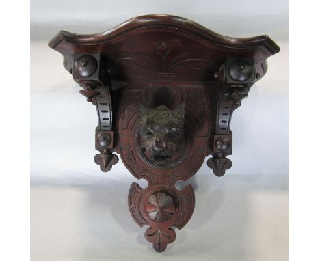 A good quality carved mahogany wall bracket in the aesthetic manner, centrally carved with the bust of a snarling big cat, un